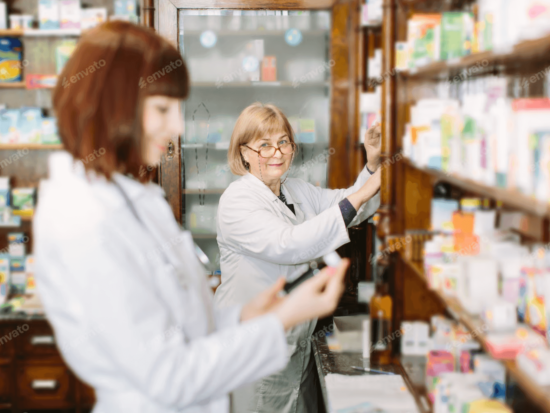 Zwei Apothekerinnen stehen vor einem Apothekerschrank.